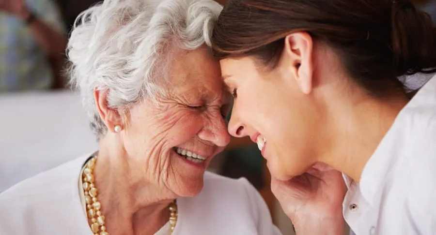 Elderly woman touching face of young female nurse