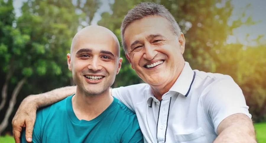 A younger man and an older man outside smiling