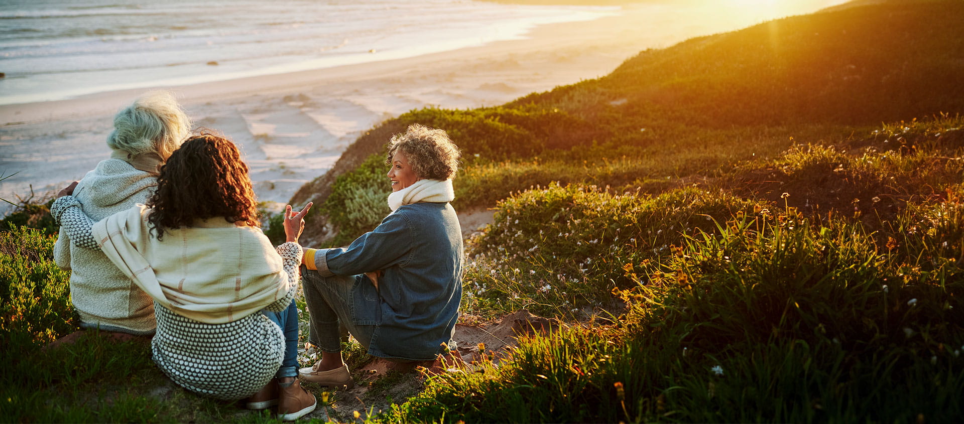 A group of three women looking over a beach sunset. 