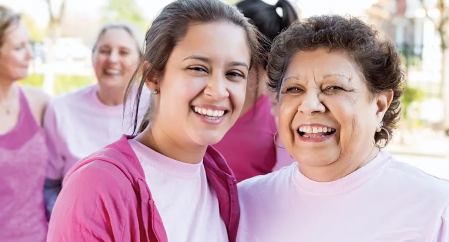 Young woman with dark pink cardigan, light pink shirt beside an older woman. Both women smiling