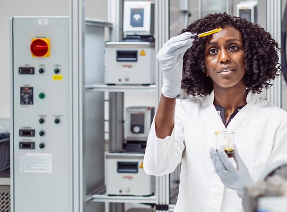 A female scientist in a lab, focused on her work with test tubes and scientific instruments on the table.