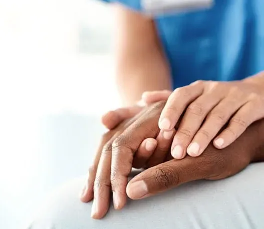 A doctor wraps both their hands around the hand of a patient