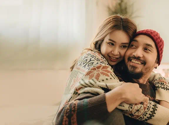 Two people sit together embracing and smiling