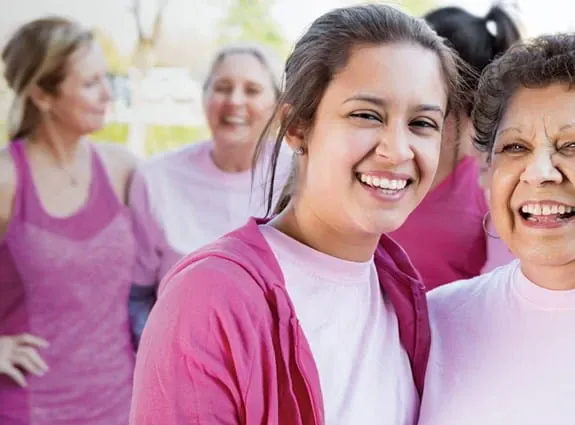 Young woman with dark pink cardigan, light pink shirt beside an older woman. Both women smiling